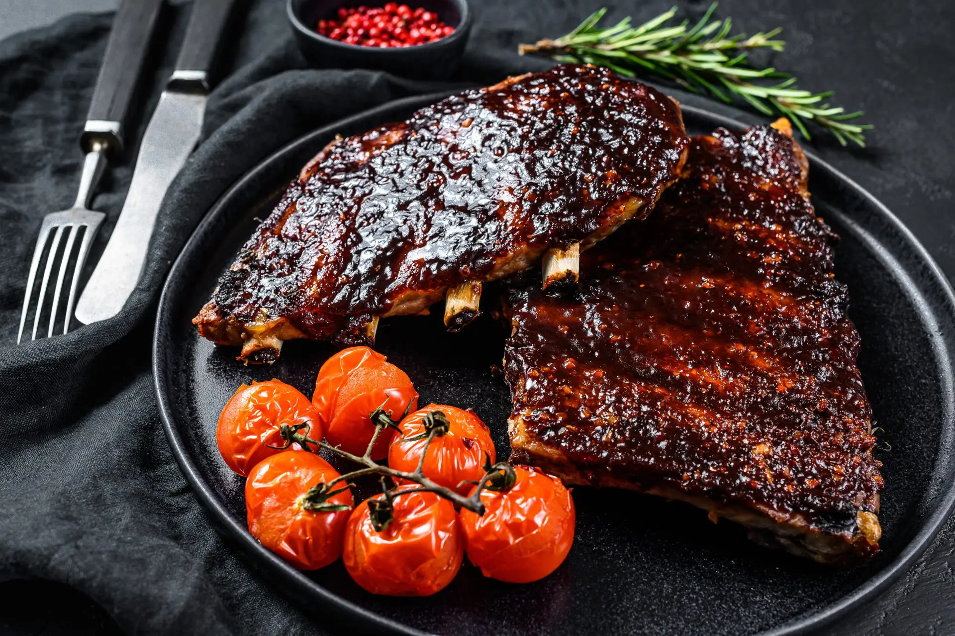 BBQ ribs on a plate with cooked vine tomato garnish
