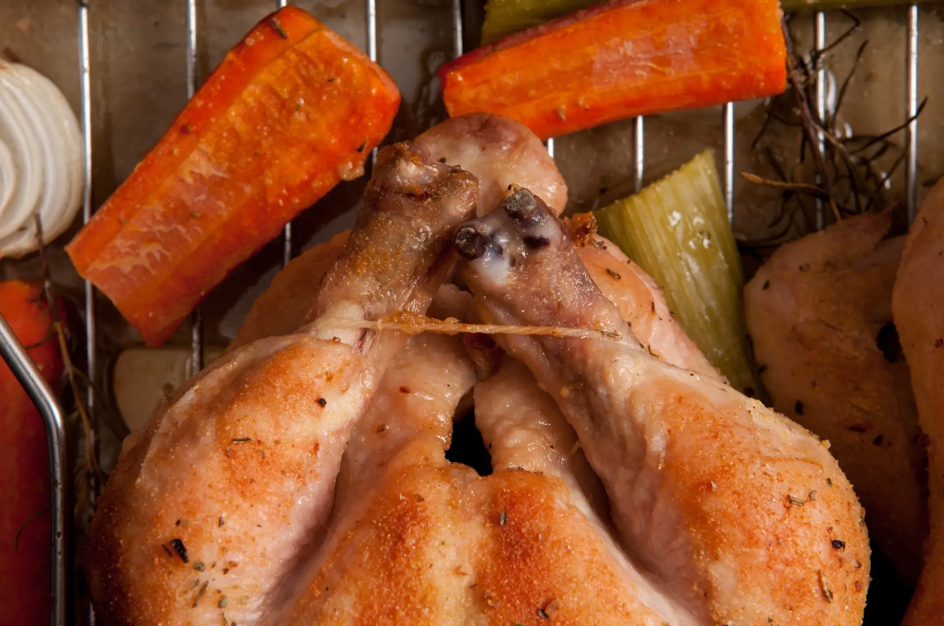 Smoked chicken legs with roasted leeks and carrots on a tray